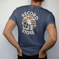 Man wearing a Navy tee, seen from the back: a scruffy rat in a beanie peeking out of a record bin, with "RECORD STORE" and "RAT" in chunky 70s lettering and small 70s caps, printed in faded, cracked cream, mustard, burnt orange and faded teal over…