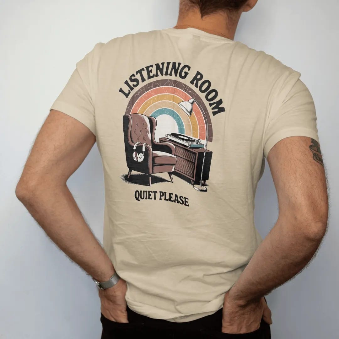 Man wearing a Sandstone tee, seen from the back: a mid-century armchair facing a turntable console with headphones, with "LISTENING ROOM" and "QUIET PLEASE" in chunky 70s lettering and small 70s caps, printed in faded, cracked brown, burnt orange,…