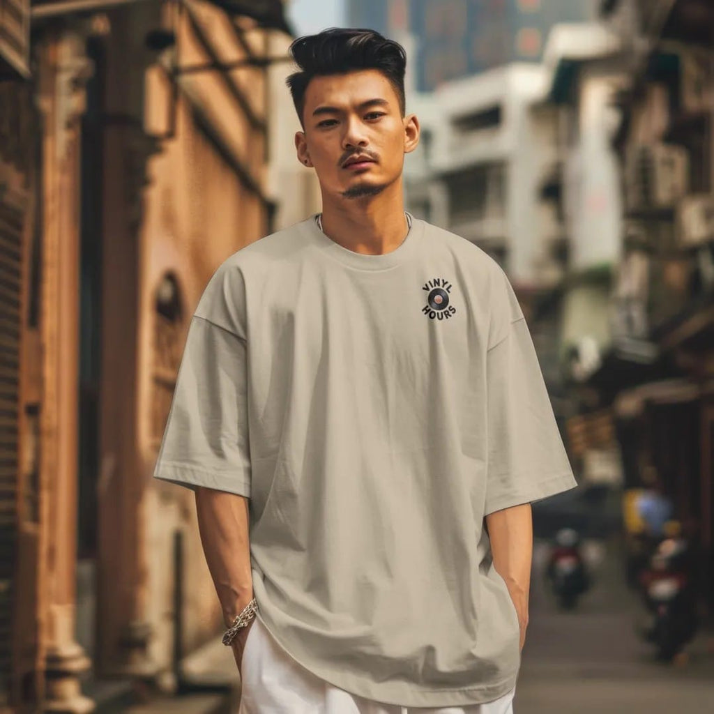 Man in a Sandstone tee on a city street, with the small Vinyl Hours logo on the left chest.