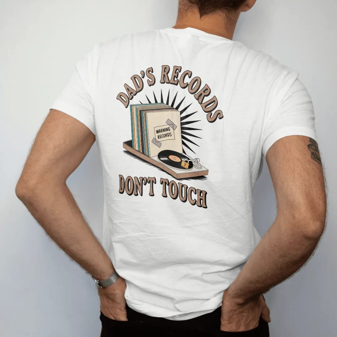 Man wearing a White tee, seen from the back: a record shelf with a taped warning sign and a padlocked turntable, with "DAD'S RECORDS" and "DON'T TOUCH" in chunky 70s lettering and small 70s caps, printed in faded, cracked cream, mustard, burnt…
