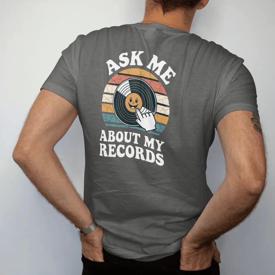 Man wearing a Pepper tee, seen from the back: a smiling record with a speech bubble and a pointing hand, with "ASK ME", "ABOUT MY" and "RECORDS" in chunky 70s lettering and small 70s caps, printed in faded, cracked cream, mustard, burnt orange and…