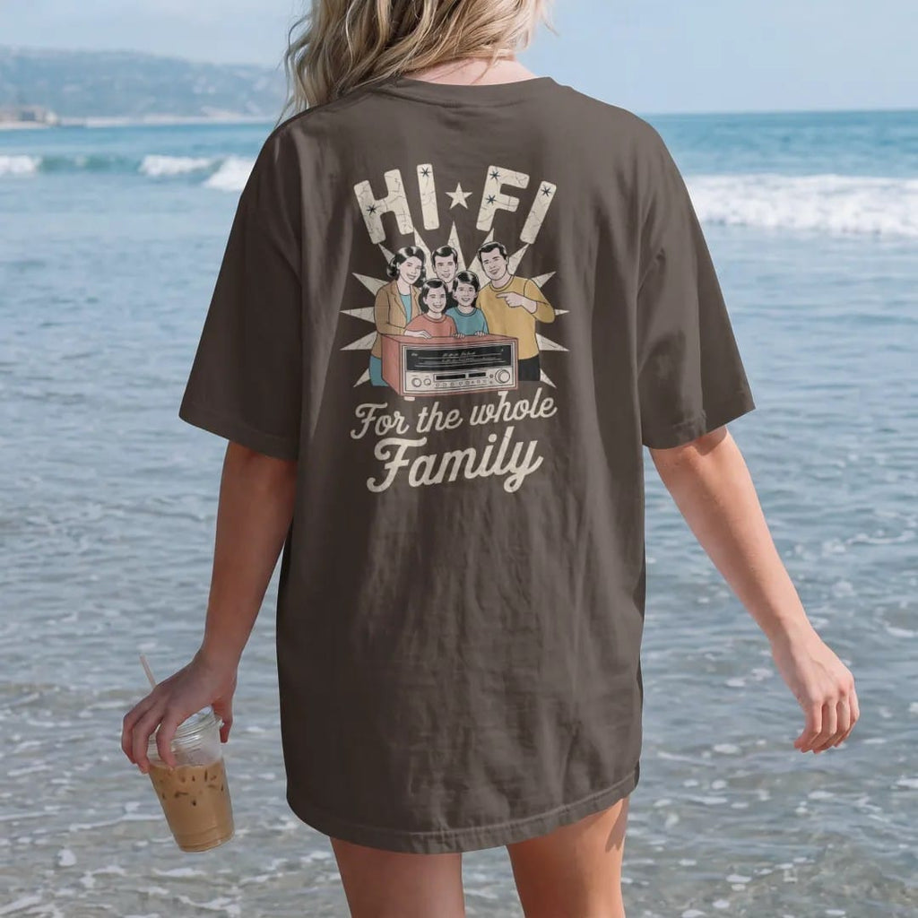 Woman on the beach in a Espresso tee, back view: a 1950s-ad family gathered around a wooden console stereo, with "HI-FI" and "FOR THE WHOLE FAMILY" in chunky 70s lettering and brush script, printed in faded, cracked cream, mustard, burnt orange and…