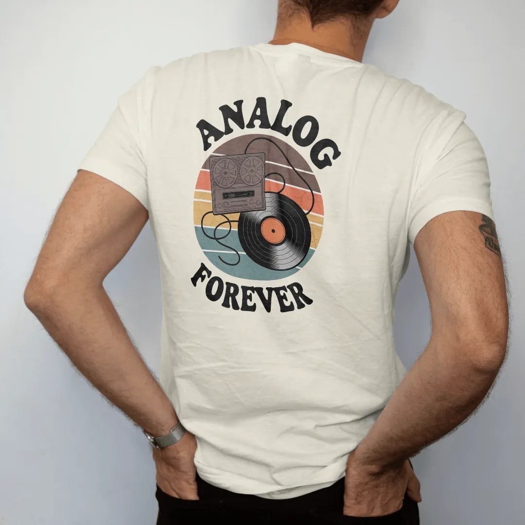 Man wearing a Ivory tee, seen from the back: a reel-to-reel and a record joined by an infinity-loop tape ribbon, with "ANALOG" and "FOREVER" in chunky 70s lettering and small 70s caps, printed in faded, cracked brown, burnt orange, faded teal and…