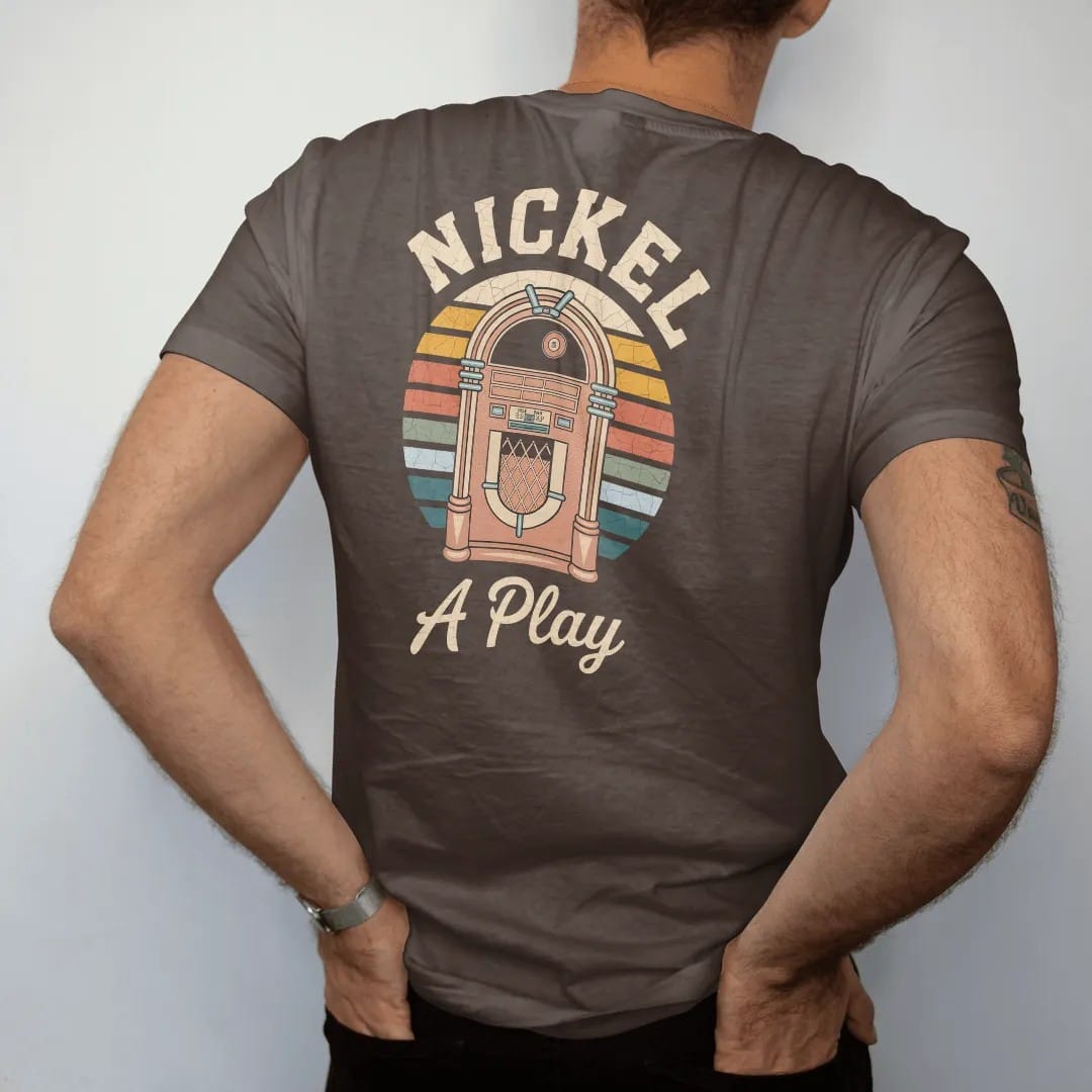 Man wearing a Espresso tee, seen from the back: a glowing arched jukebox with a nickel flying toward the slot, with "NICKEL" and "A PLAY" in chunky 70s lettering and brush script, printed in faded, cracked cream, mustard, burnt orange and faded…