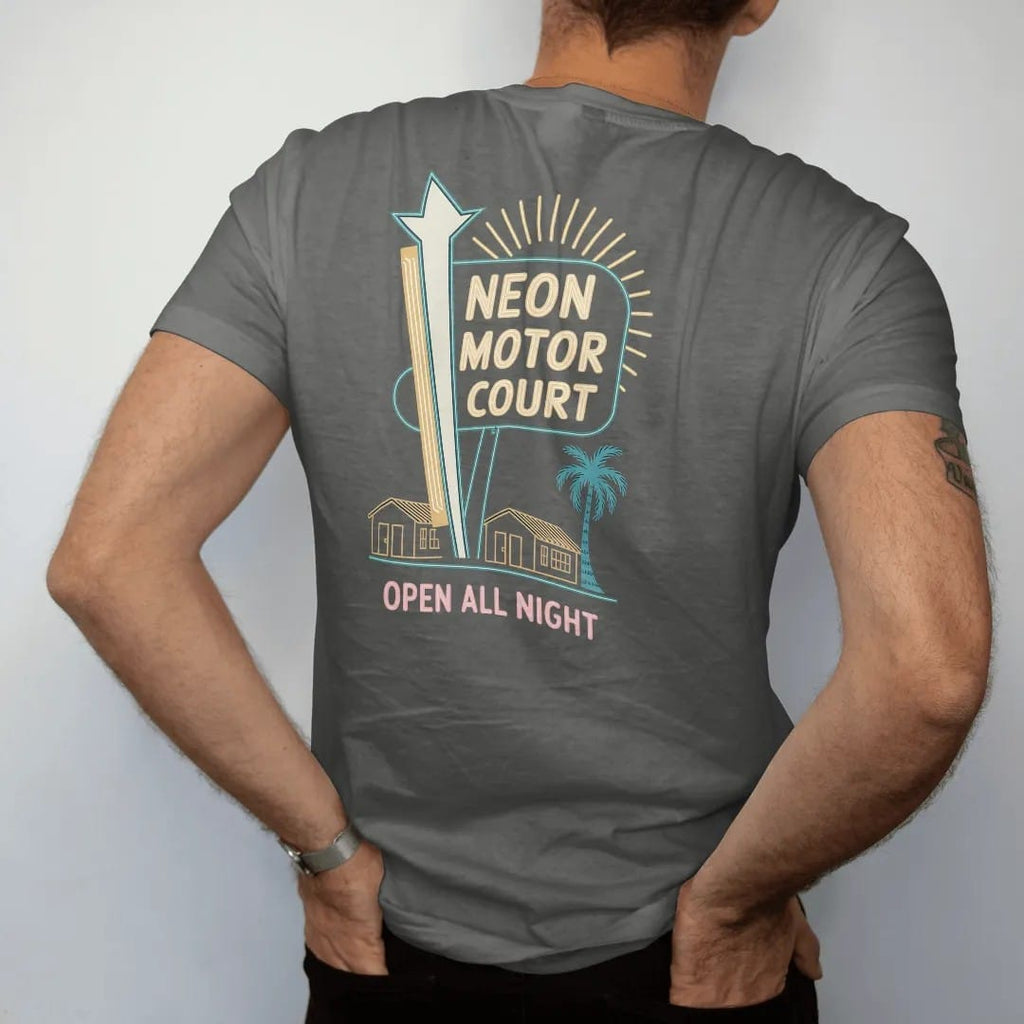 Man wearing a Pepper tee, seen from the back: a tall neon motel sign with a starburst over little bungalows, with "NEON MOTOR COURT" and "OPEN ALL NIGHT" in neon-tube script and small 70s caps, printed in faded, cracked cream, mustard and turquoise…