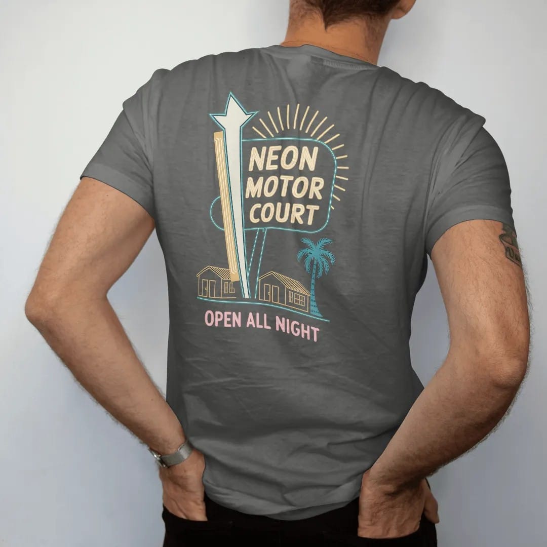 Man wearing a Pepper tee, seen from the back: a tall neon motel sign with a starburst over little bungalows, with "NEON MOTOR COURT" and "OPEN ALL NIGHT" in neon-tube script and small 70s caps, printed in faded, cracked cream, mustard and turquoise…