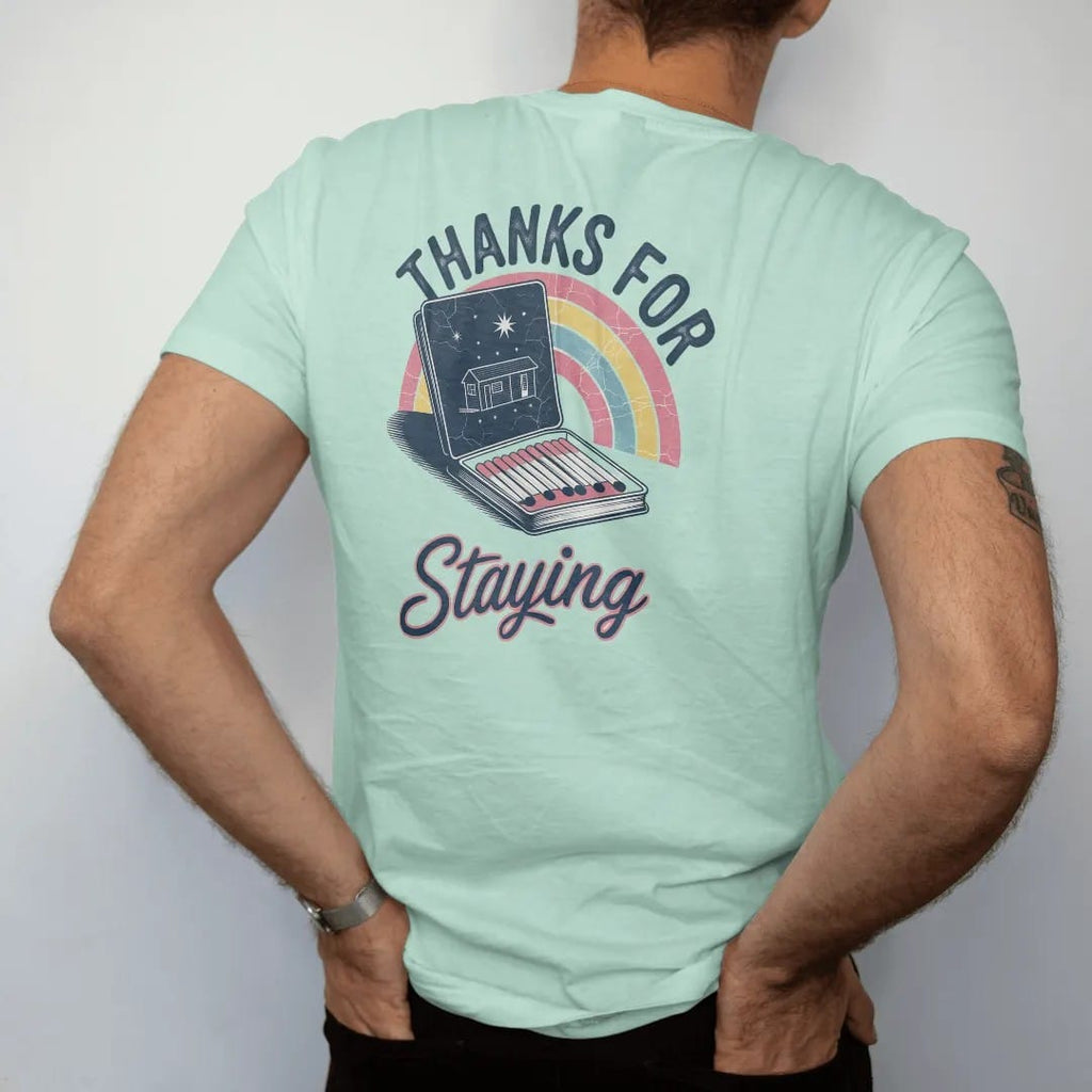 Man wearing a Chalky Mint tee, seen from the back: an open vintage motel matchbook with a motel drawing on the cover, with "THANKS FOR" and "STAYING" in chunky 70s lettering and brush script, printed in faded, cracked navy, rust red and dusty teal…