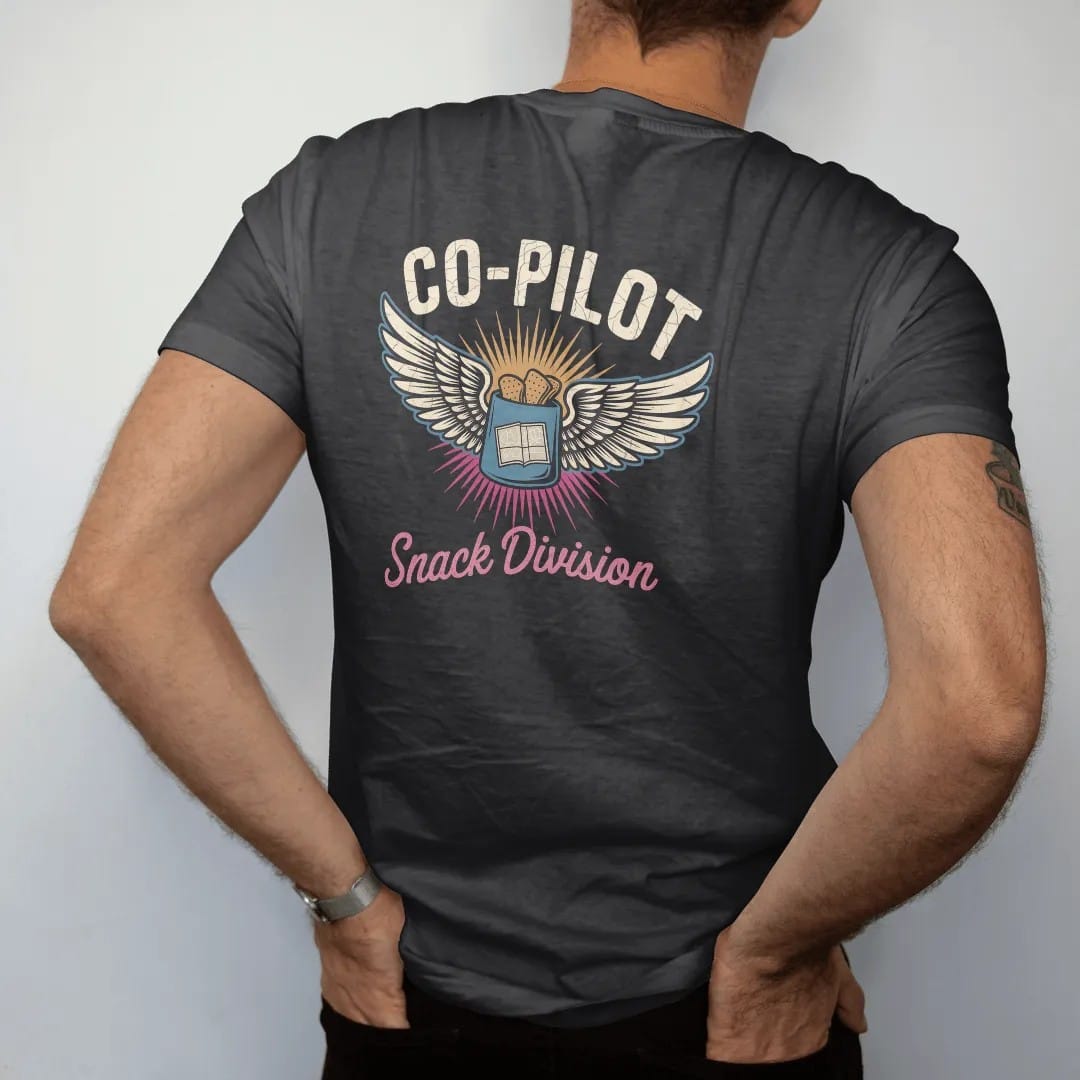 Man wearing a Black tee, seen from the back: a winged pilot badge with crossed chips bag and paper map, with "CO-PILOT" and "SNACK DIVISION" in chunky 70s lettering and brush script, printed in faded, cracked cream, mustard and turquoise with a…