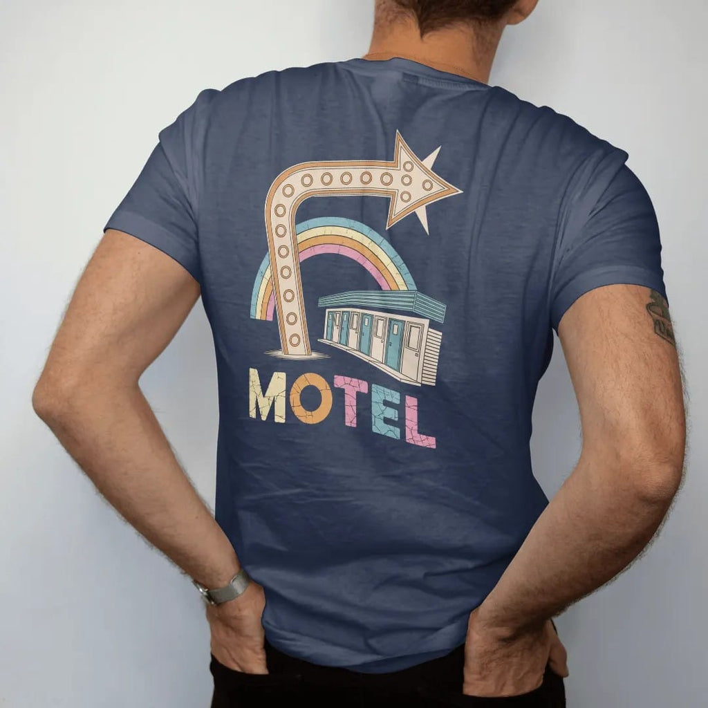 Man wearing a Navy tee, seen from the back: a huge bulb-lit curved arrow pointing at motel doors, with "MOTEL" in chunky 70s lettering, printed in faded, cracked cream, mustard and turquoise with a neon pink accent over a faded rainbow arc.