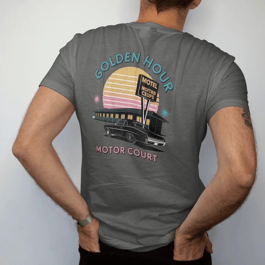 Man wearing a Pepper tee, seen from the back: a motel row and tall sign silhouetted against a striped setting sun, with "GOLDEN HOUR" and "MOTOR COURT" in chunky 70s lettering and small 70s caps, printed in faded, cracked cream, mustard and…