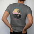 Man wearing a Pepper tee, seen from the back: a motel row and tall sign silhouetted against a striped setting sun, with "GOLDEN HOUR" and "MOTOR COURT" in chunky 70s lettering and small 70s caps, printed in faded, cracked cream, mustard and…
