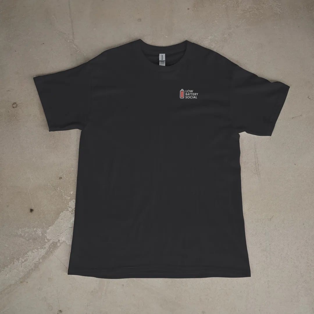 Front of a Black tee laid flat, with the small Low Battery Social logo on the left chest.