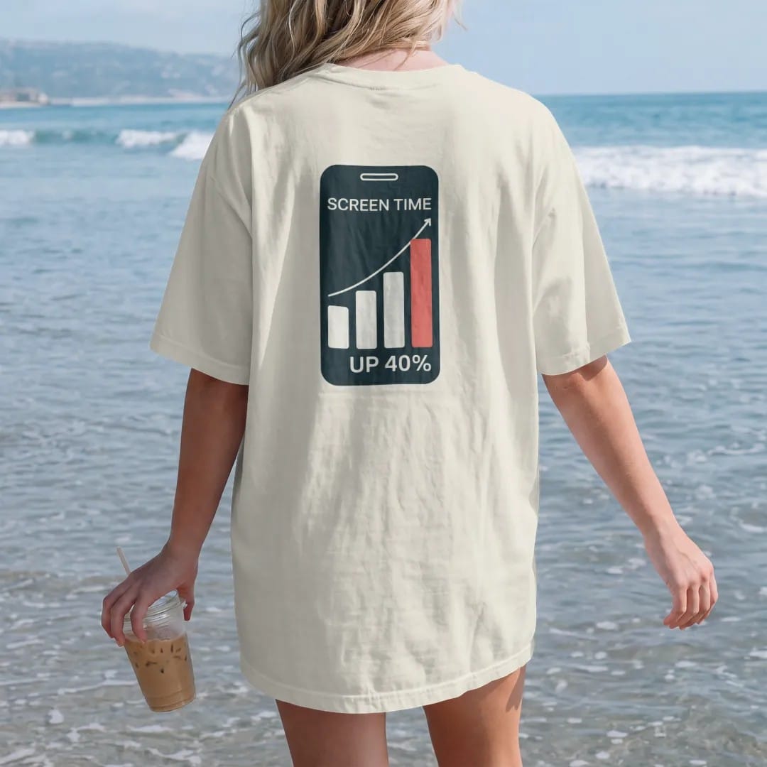Woman on the beach in a Ivory tee, back view: minimal single-line drawing of a phone outline with a simple rising bar graph on the screen, with "SCREEN TIME / UP 40%" in small spaced-out caps, printed in bone white with a low-battery red accent on…