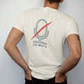 Man wearing a Ivory tee, seen from the back: minimal single-line drawing of a microphone outline with one diagonal slash through it, with "YOU'RE ON MUTE" in small spaced-out caps, printed in ink navy with a battery red accent on the slash.