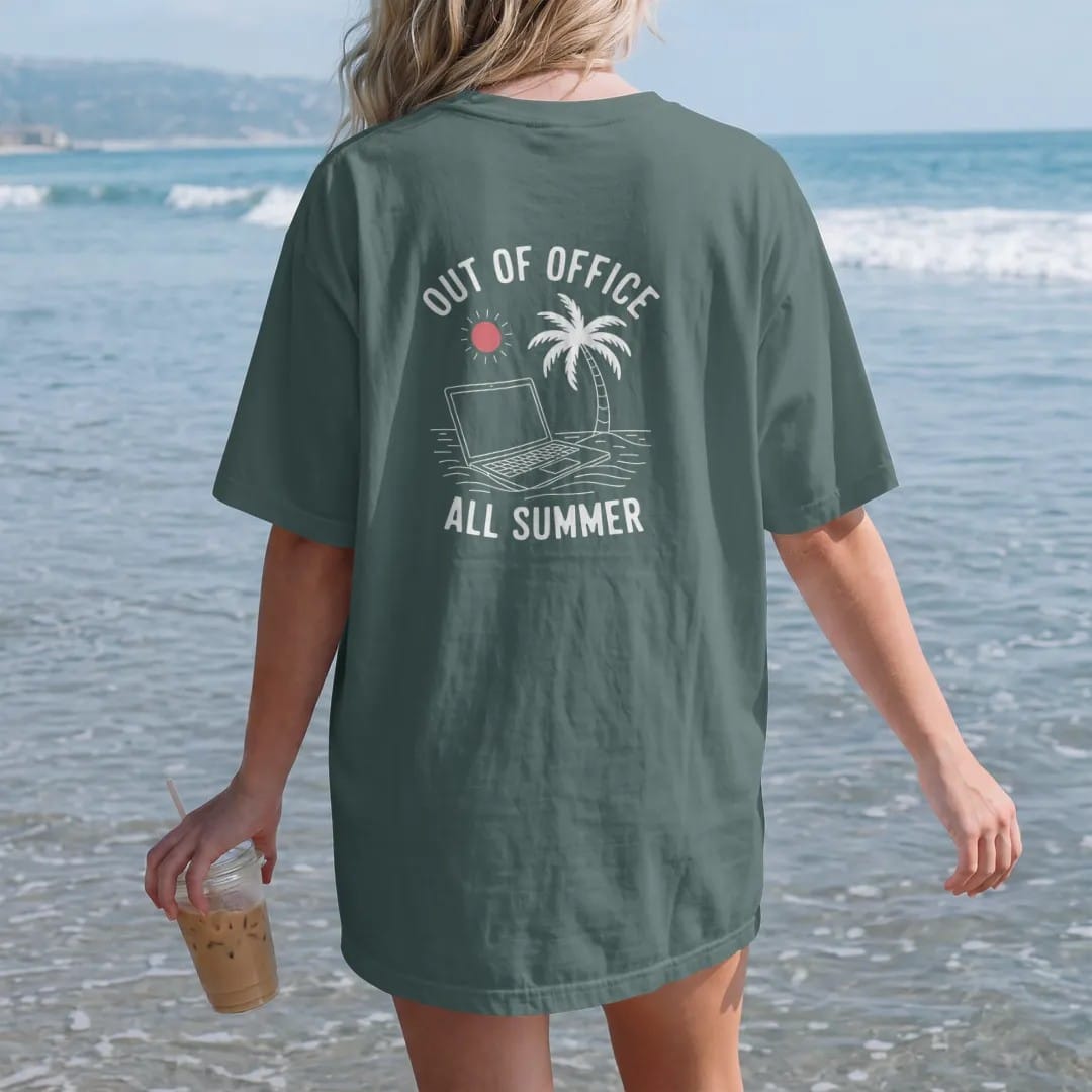 Woman on the beach in a Blue Spruce tee, back view: minimal single-line drawing of a closed laptop half buried in sand under a single palm tree and a small sun, with "OUT OF OFFICE / ALL SUMMER" in small spaced-out caps, printed in bone white with…