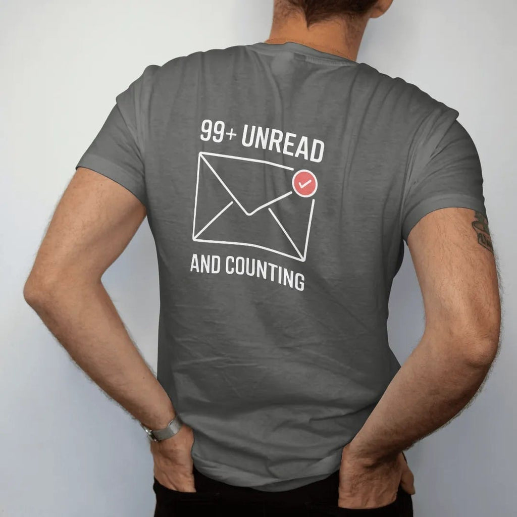 Man wearing a Pepper tee, seen from the back: minimal single-line drawing of an envelope outline with a small round notification badge on its corner, with "99+ UNREAD / AND COUNTING" in small spaced-out caps, printed in bone white with a…
