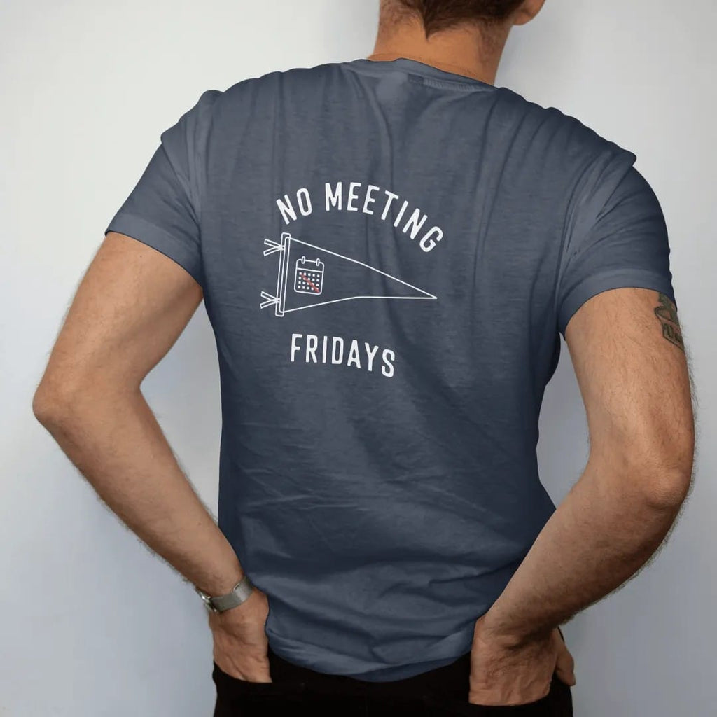 Man wearing a Midnight tee, seen from the back: minimal single-line drawing of a slim pennant outline with a small crossed-out calendar icon, with "NO MEETING / FRIDAYS" in small spaced-out caps, printed in bone white with a low-battery red accent…