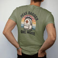 Man wearing a Moss tee, seen from the back: a cartoon backpack stuffed with tiny mountain peaks poking out of the top, shield badge, faded 70s souvenir style, lettered "PEAK BAGGER / ONE MORE" in chunky rounded 70s letters with a drop shadow,…