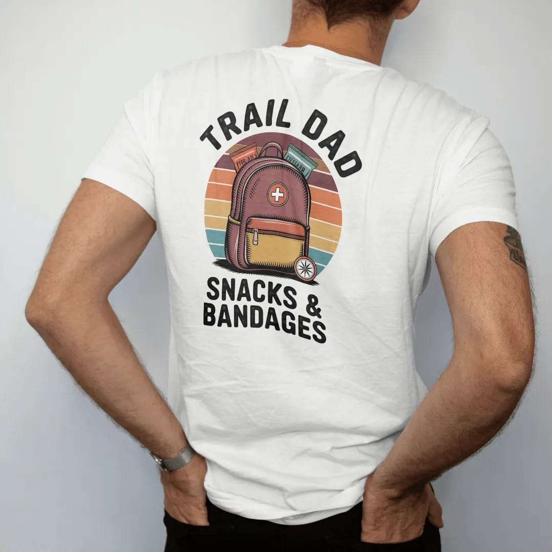 Man wearing a White tee, seen from the back: a fully loaded daypack with a first-aid patch, snacks peeking out and a small compass, faded 70s souvenir style, lettered "TRAIL DAD / SNACKS & BANDAGES" in chunky rounded 70s letters with a drop shadow,…