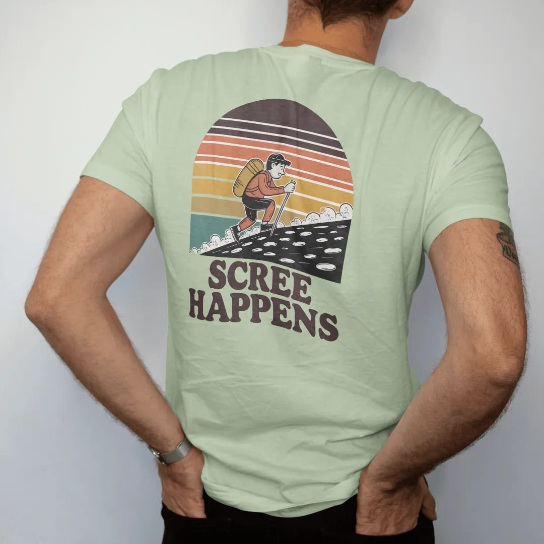 Man wearing a Light Green tee, seen from the back: a cartoon hiker sliding down a slope of loose rocks with little dust clouds, faded 70s souvenir style, lettered "SCREE HAPPENS" in chunky rounded 70s letters with a drop shadow, printed in faded…