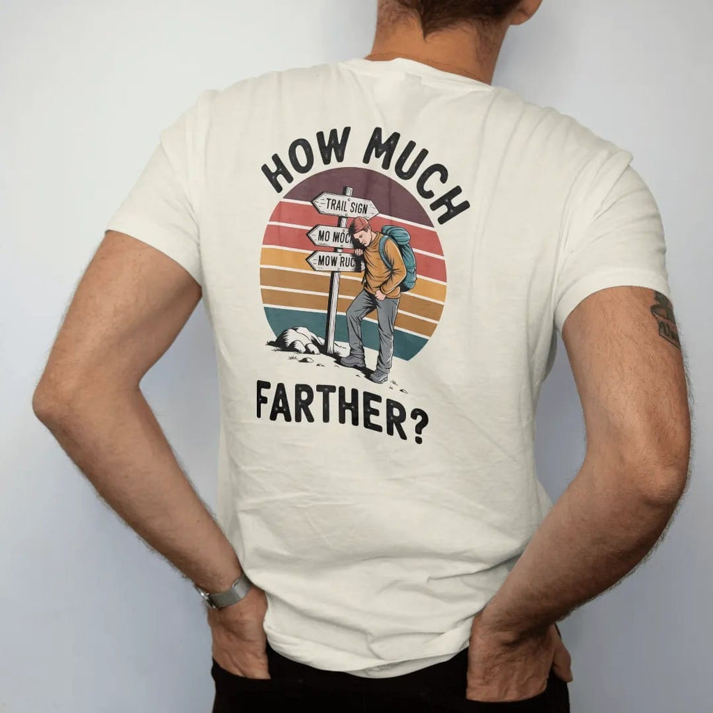 Man wearing a Ivory tee, seen from the back: a trail sign with mileage numbers crossed out and rewritten higher, a tired hiker leaning on it, faded 70s souvenir style, lettered "HOW MUCH / FARTHER?" in chunky rounded 70s letters with a drop shadow,…