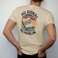 Man wearing a Sandstone tee, seen from the back: a folded paper map with a compass on top and a crossed-out phone signal icon, faded 70s souvenir style, lettered "NO SIGNAL / NO PROBLEM" in chunky rounded 70s letters with a drop shadow, printed in…