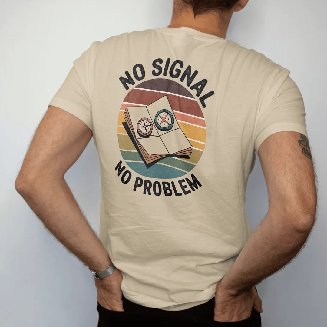 Man wearing a Sandstone tee, seen from the back: a folded paper map with a compass on top and a crossed-out phone signal icon, faded 70s souvenir style, lettered "NO SIGNAL / NO PROBLEM" in chunky rounded 70s letters with a drop shadow, printed in…