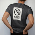 Man wearing a Black tee, seen from the back: a warning-sign parody with a no-symbol over a decaf cup, No Decaf in caps and Beyond This Point below, drawn in a single fine crema-cream line with one burnt copper accent.