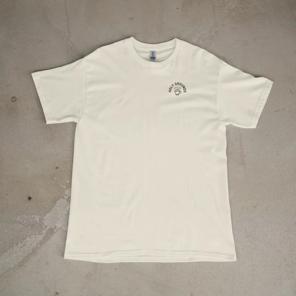 Front of a Ivory tee laid flat, with the small Holy Grounds logo on the left chest.