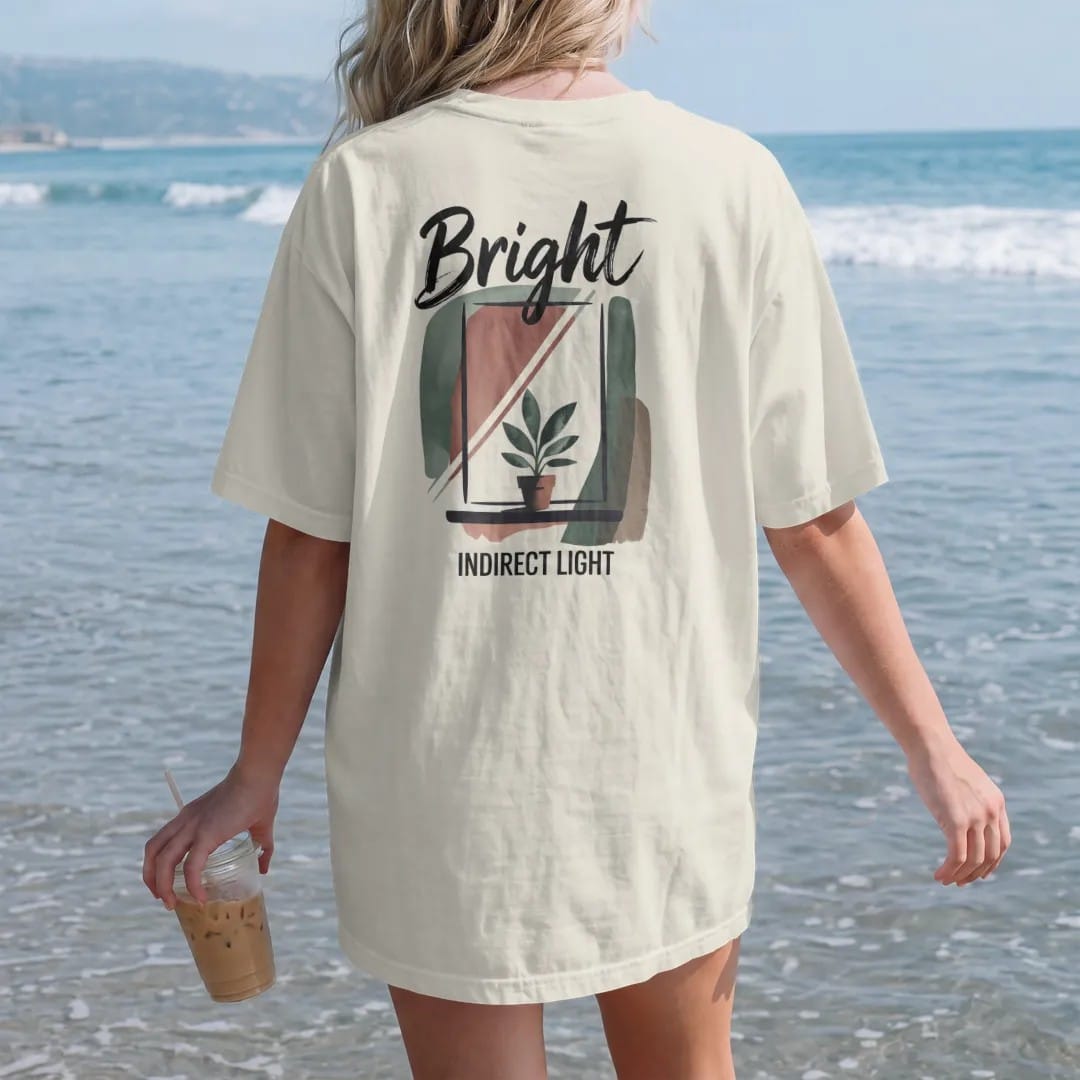 Woman on the beach in a Ivory tee, back view: a simple window with soft angled light rays falling on a small potted plant, "BRIGHT" in loose brush script above and "INDIRECT LIGHT" small below, painted in loose watercolor and ink with soft deep…