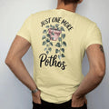 Man wearing a Butter tee, seen from the back: a trailing pothos vine draping from a small hanging pot with heart-shaped leaves, "JUST ONE MORE" in small brush-written caps above and "POTHOS" in loose brush script below, painted in loose watercolor…