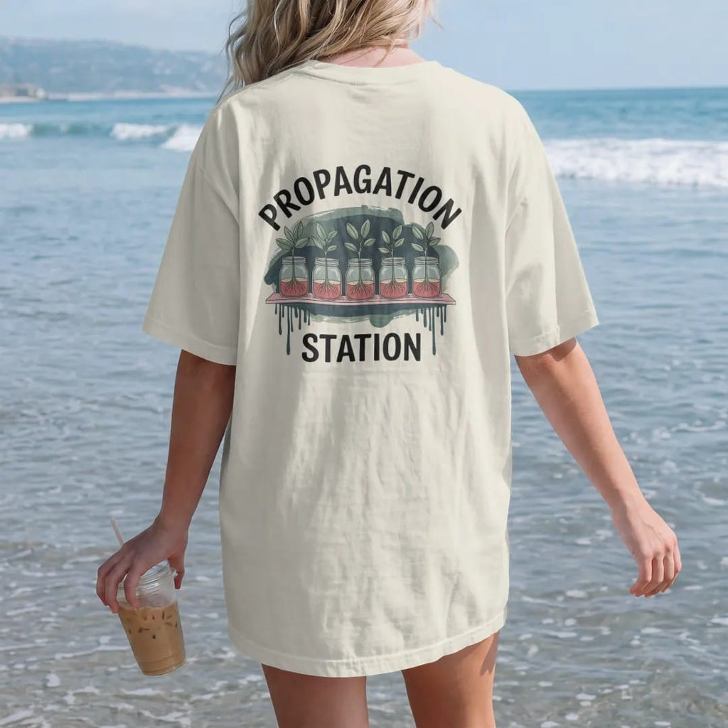 Woman on the beach in a Ivory tee, back view: a row of three small glass jars with rooting cuttings on a thin shelf, "PROPAGATION" arched above and "STATION" small below in small brush-written caps, painted in loose watercolor and ink with soft…