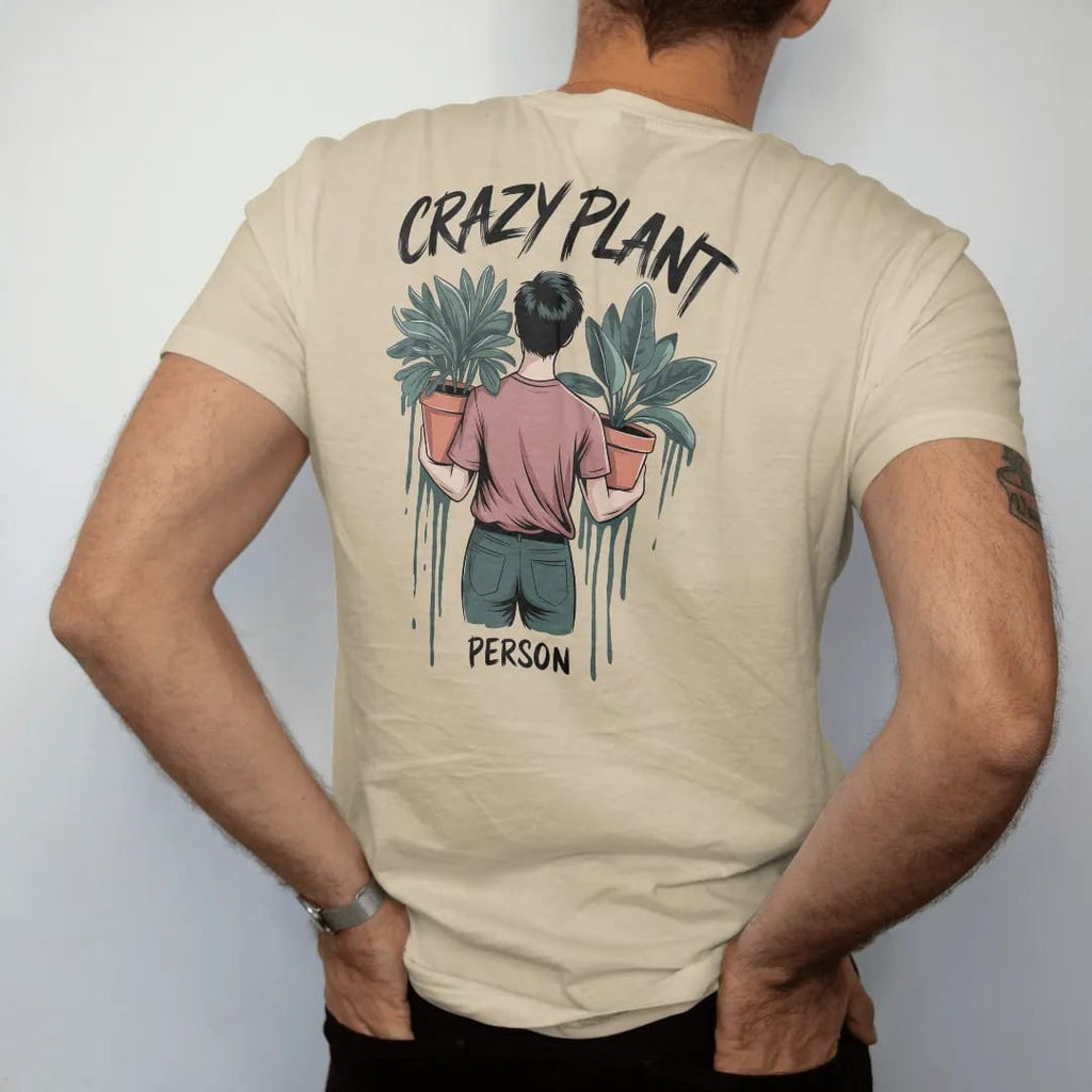Man wearing a Sandstone tee, seen from the back: a figure holding an armful of potted plants, "CRAZY PLANT" in loose brush script above and "PERSON" small below, painted in loose watercolor and ink with soft deep green, terracotta, soil brown and…