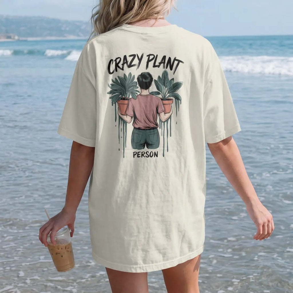 Woman on the beach in a Ivory tee, back view: a figure holding an armful of potted plants, "CRAZY PLANT" in loose brush script above and "PERSON" small below, painted in loose watercolor and ink with soft deep green, terracotta, soil brown and moss…