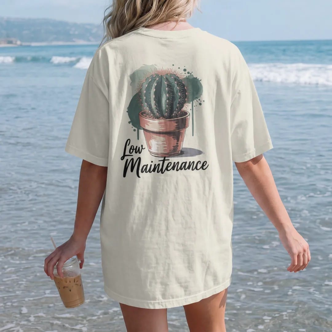 Woman on the beach in a Ivory tee, back view: a single round cactus in a small terracotta pot, small brush-written caps "LOW MAINTENANCE" beneath, painted in loose watercolor and ink with soft deep green, terracotta, soil brown and moss washes.