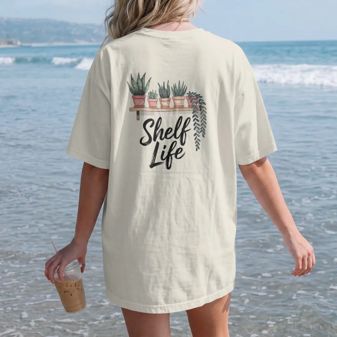 Woman on the beach in a Ivory tee, back view: a minimal floating shelf holding four small pots with different plants, trailing leaves hanging over the edge, "SHELF LIFE" in loose brush script beneath, painted in loose watercolor and ink with soft…