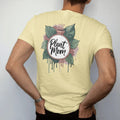Man wearing a Butter tee, seen from the back: a neat round badge framed by two pothos leaves with a small pot in the center, "PLANT MOM" in loose brush script across the bottom, painted in loose watercolor and ink with soft deep green, terracotta,…