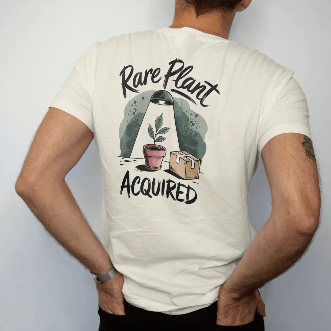 Man wearing a Ivory tee, seen from the back: a single small pot with one prized leaf under a tiny spotlight, a little cardboard shipping box beside it, "RARE PLANT" in loose brush script above and "ACQUIRED" below, painted in loose watercolor and…