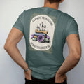 Man wearing a Blue Spruce tee, seen from the back: back print: A heap of quartz points, amethyst geodes and tumbled stones, stacked text "I'M NOT HOARDING" above and "IT'S A COLLECTION" below the pile, antique apothecary-label engraving, fine…
