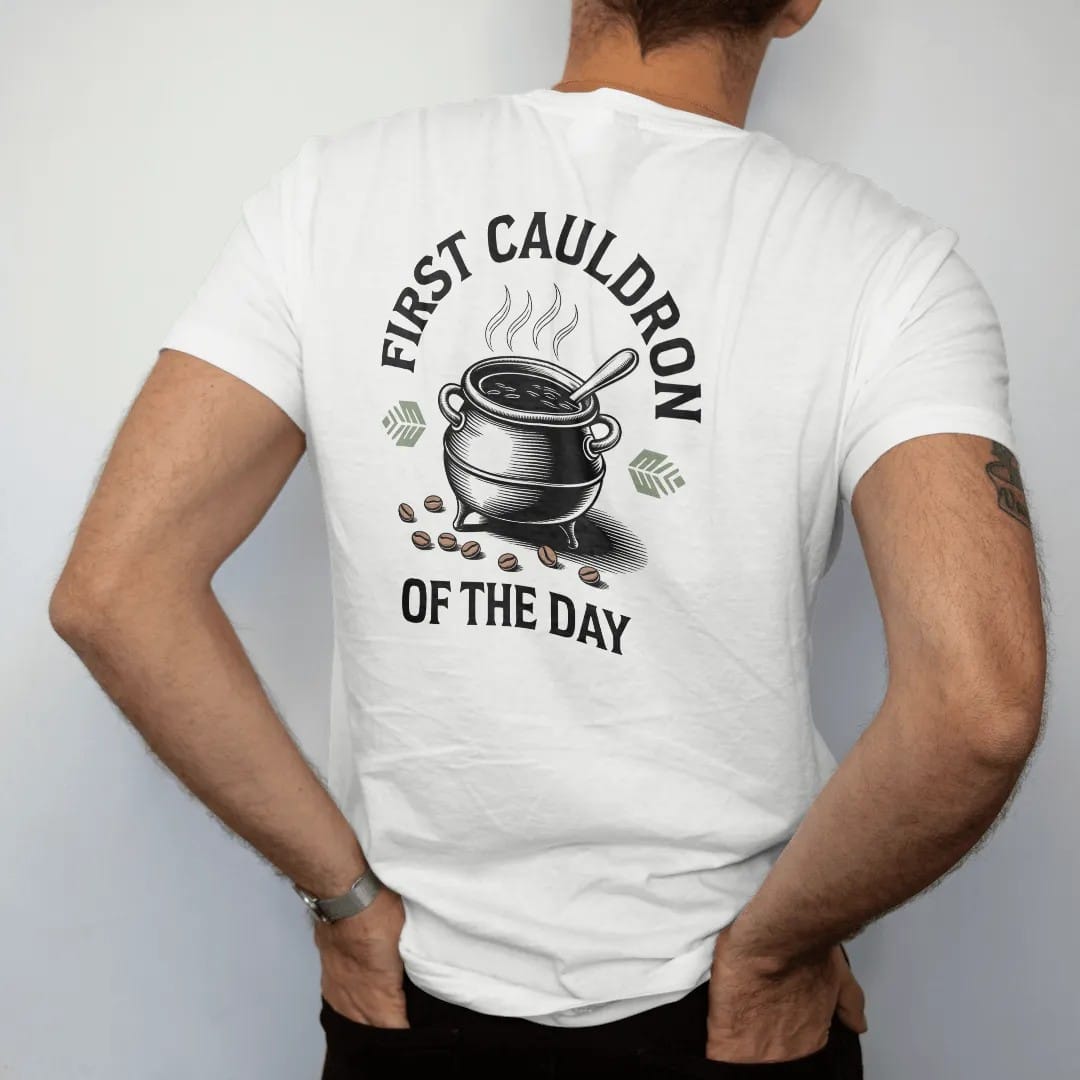 Man wearing a White tee, seen from the back: back print: A small iron cauldron full of steaming coffee with scattered coffee beans and a spoon, arched "FIRST CAULDRON" with "OF THE DAY" below, detailed vintage etching, fine crosshatching and…