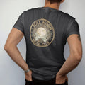 Man wearing a Black tee, seen from the back: back print: A club emblem with a full moon, crossed brooms and sage leaves, round badge, "FULL MOON" arched top, "SOCIAL CLUB" arched bottom, "EST. AFTER DARK" in a center ribbon, detailed vintage…