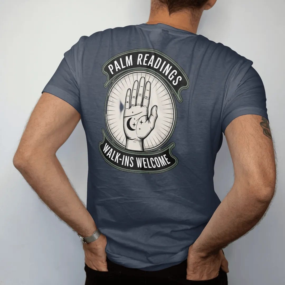 Man wearing a Midnight tee, seen from the back: back print: an open palm with fine lines drawn in and a crescent moon and stars at the fingertips, vintage storefront sign with "PALM READINGS" on top and "WALK-INS WELCOME" below, detailed vintage…