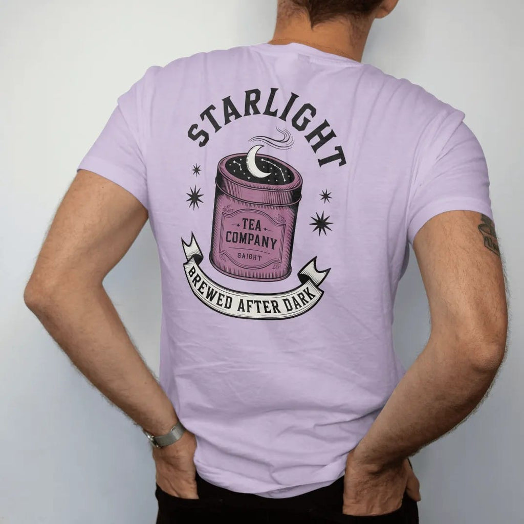 Man wearing a Orchid tee, seen from the back: back print: A vintage tea tin with a crescent moon and constellations on the lid and steam curling up, "STARLIGHT" arched above, "TEA COMPANY" on the tin and "BREWED AFTER DARK" in a ribbon below,…