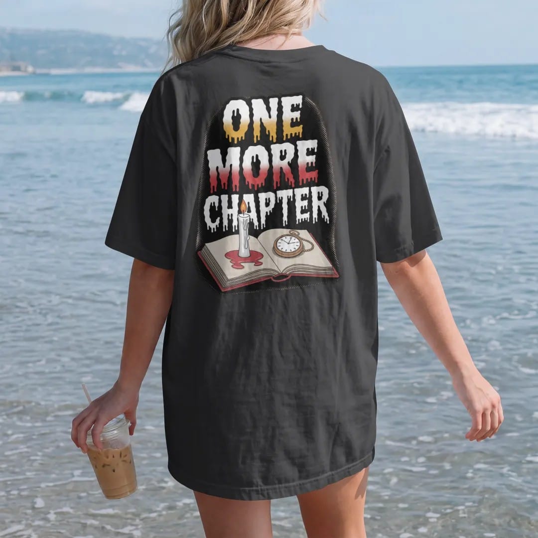 Woman on the beach in a Black tee, back view: a melted candle stub on an open book next to a cracked pocket watch with One More Chapter stacked above and below, in pulp halftone cream, red, yellow and blue.