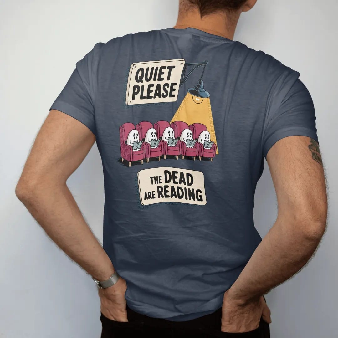 Man wearing a Midnight tee, seen from the back: a library placard reading Quiet Please over a row of small ghosts reading in armchairs, with The Dead Are Reading below, in pulp halftone cream, red, yellow and blue.