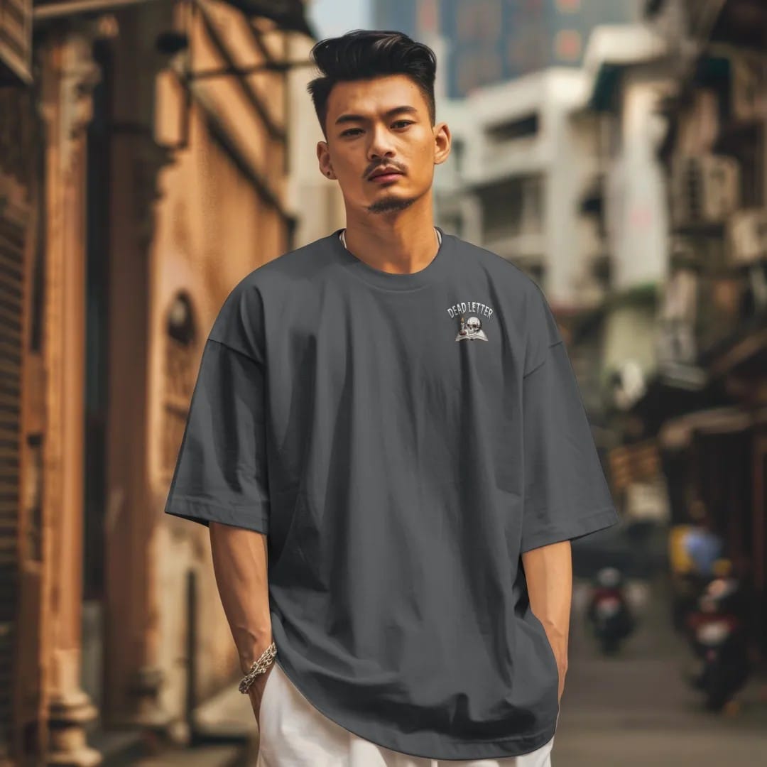 Man in a Graphite tee on a city street, with the small Dead Letter Book Club logo on the left chest.