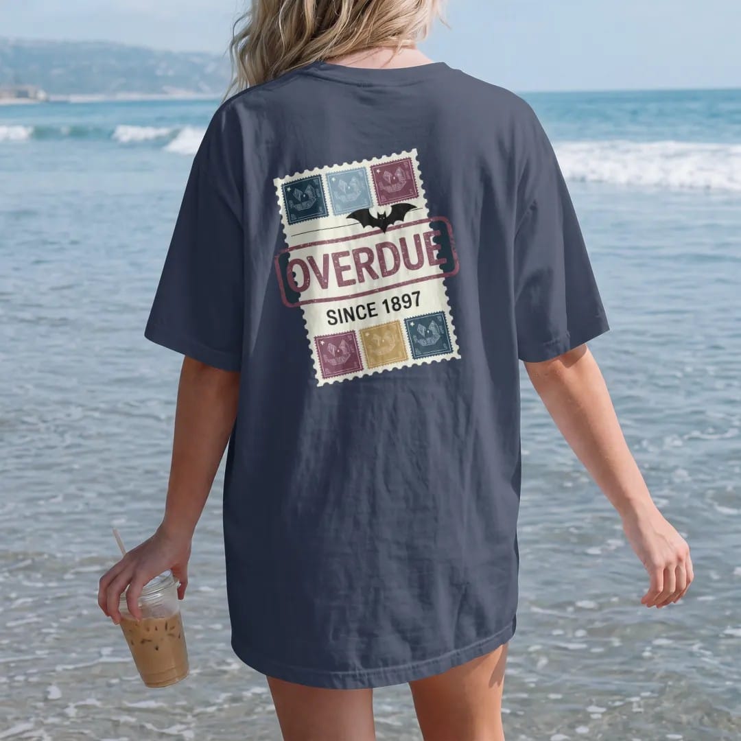 Woman on the beach in a Navy tee, back view: a vintage library due-date card with a big slanted Overdue stamp, Since 1897 stamped below and a small bat clipped on, in pulp halftone navy, red, mustard and teal.