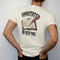 Man wearing a Ivory tee, seen from the back: an annotated open book full of tabs with a dripping quill leaning on it, Annotated above and In Red Ink below, in pulp halftone cream, red, yellow and blue.