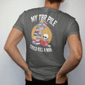 Man wearing a Pepper tee, seen from the back: a towering wobbling book stack leaning over a nervous skeleton holding a teacup, with My TBR Pile above and Could Kill A Man below, in pulp halftone cream, red, yellow and blue.