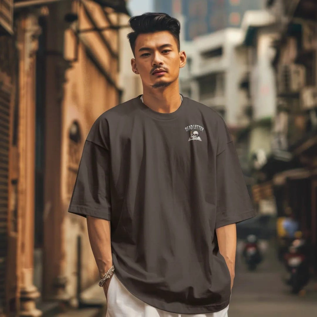 Man in a Espresso tee on a city street, with the small Dead Letter Book Club logo on the left chest.